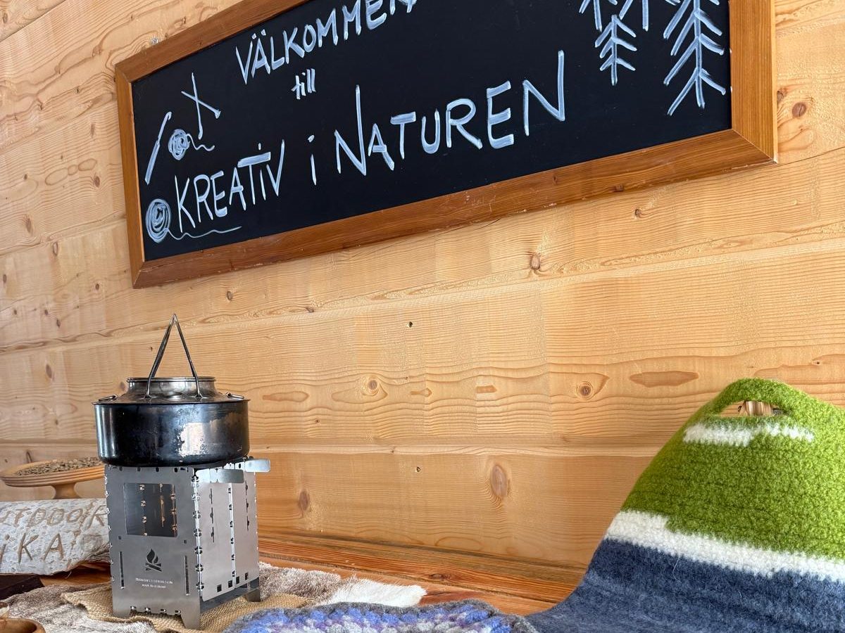 Två personer i skogen delar på mat och dryck, omgivna av höstfärgad natur.