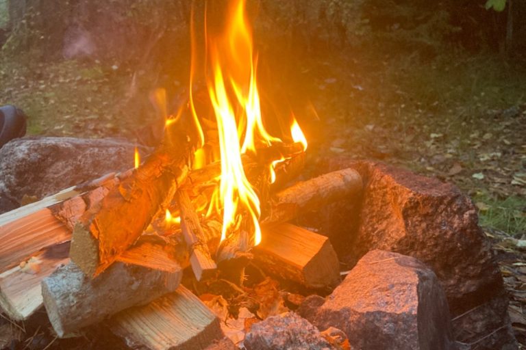 Tre personer i kajaker på en sjö, omgivna av träd och en molnig himmel.