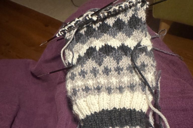 Två personer paddlar kajak på en stilla sjö omgiven av höstfärger.