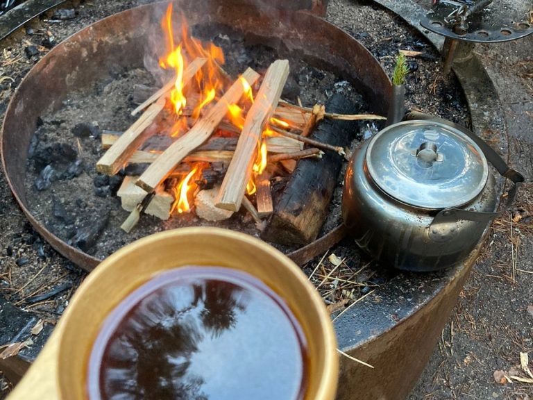 En eld där kaffet kokat och du kan dricka ur en träkåsa
